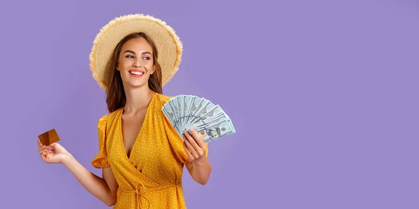Kaukasische Zwanzigjährige mit Strohhut und Kreditkarte und Fan von Dollargeld isoliert vor lila Hintergrund — Stockfoto