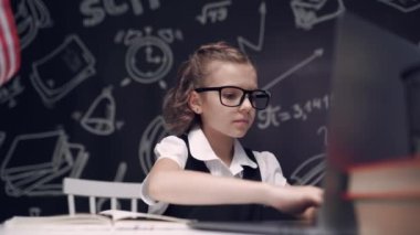 Dizüstü bilgisayarla çalışan genç bir öğrenci internette araştırma ödevi yapıyor, beyaz beyaz bir genç kız bilgisayar kullanıyor ve deftere bir şeyler yazıyor.