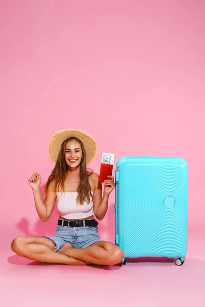 Женщина турист, путешественница с паспортом и билетами, чемодан, белый топ, шорты, соломенная шляпа. — стоковое фото
