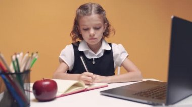 Kulaklıklı neşeli küçük kız internetten bilgisayar kullanarak e-öğrenim sistemini inceliyor..