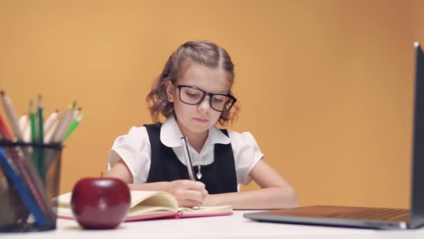 Веселая маленькая девочка в наушниках с помощью ноутбука изучает через систему электронного обучения онлайн. — стоковое видео