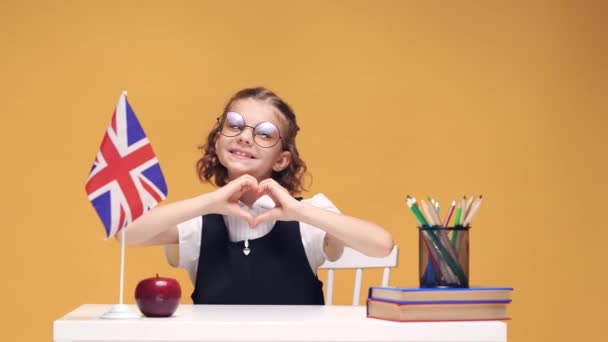 Счастливый ученик, сидящий в классе и улыбающийся камере, изучающий английский как иностранный язык, начальная школа . — стоковое видео