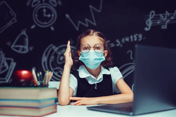 Junior student bär medicinsk mask på nätet virtuell inlärning språk klass på bärbar dator. — Stockfoto