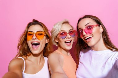 Üç komik, eğlenceli, duygusal, anlamlı, güzel kızın kendi portresi, pembe arka planda poz veren jest, doğum günü, kadın günü, bahar