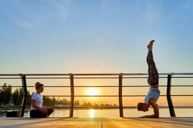 Çift açık denizde doğada akrobatik yoga yapıyor..