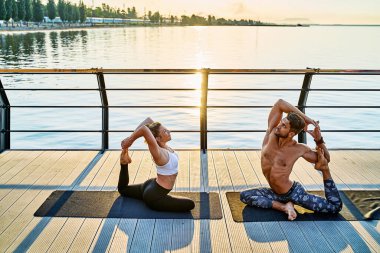 Çiftler doğada birlikte yoga yapıyorlar. Sabah egzersizleri gün doğumunda..