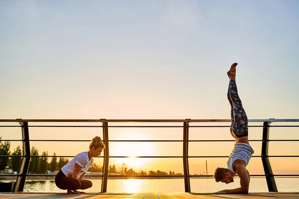 Pár cvičení akrobatické jógy společně, dělat Handstand pózovat na přírodě venku na moři. — Stock fotografie