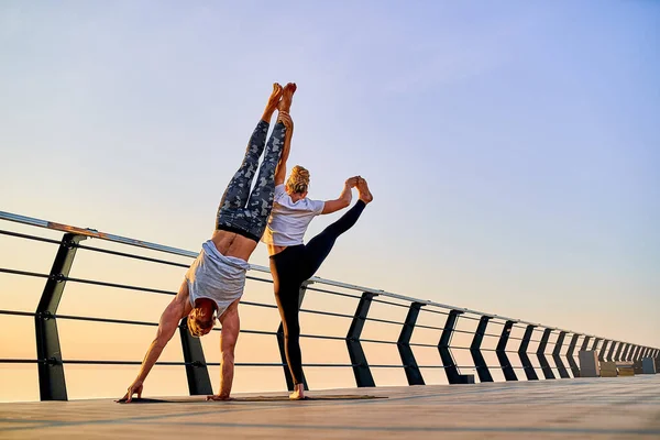 Pár cvičení akrobatické handstand jógy společně na přírodě venku na moři. — Stock fotografie
