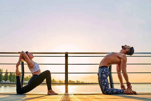 Pareja practicando yoga acrobático juntos en la naturaleza al aire libre en el mar. —  Fotos de Stock