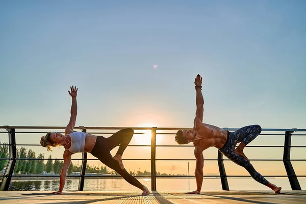 Pareja practicando yoga acrobático juntos en la naturaleza al aire libre en el mar. —  Fotos de Stock