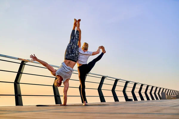 Pár cvičení akrobatické handstand jógy společně na přírodě venku na moři. — Stock fotografie