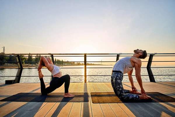 Pareja practicando yoga acrobático juntos en la naturaleza al aire libre en el mar. —  Fotos de Stock