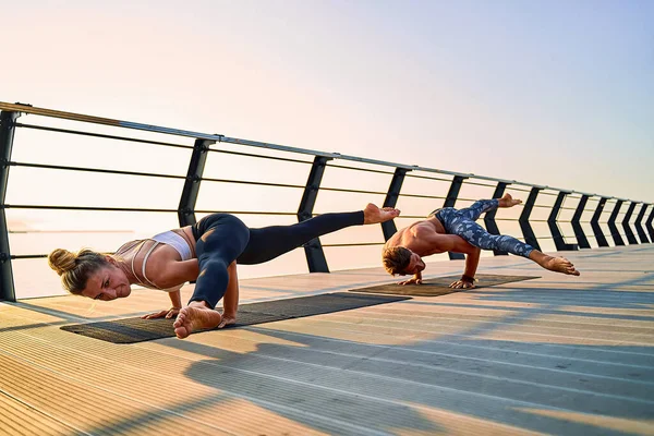 Pár cvičení akrobatické jógy společně na přírodě venku na moři. — Stock fotografie