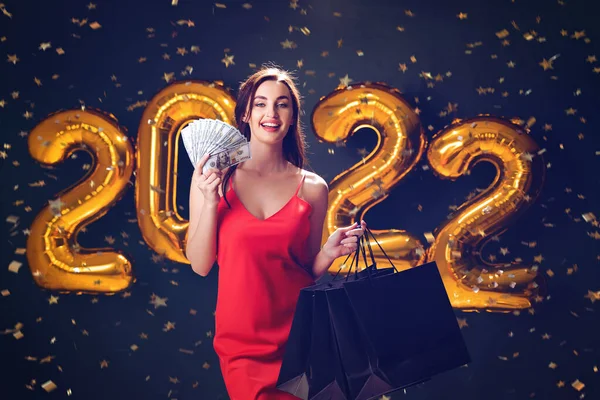 Woman with dollars and purchases. New Year shopping. Black Friday. 2022 balloons. sales. Celebrate