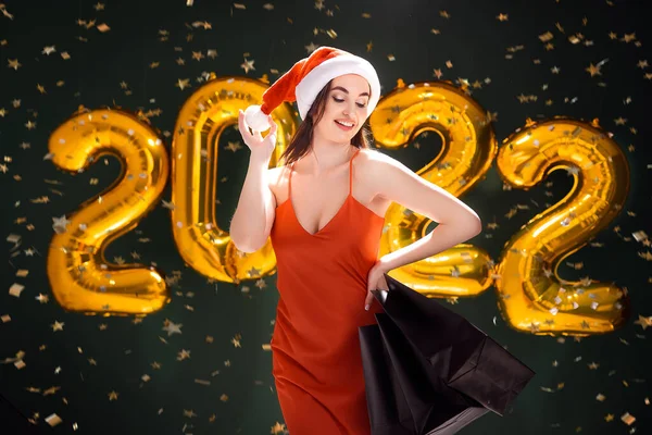 Женщина с покупками в шляпе Санты. Новогодние покупки. Черная пятница. 2022 воздушных шара. Продажи — стоковое фото
