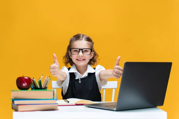 Aluna caucasiana feliz no laptop gesticulando polegares para cima sentado na mesa. Conceito de educação à distância — Fotografia de Stock