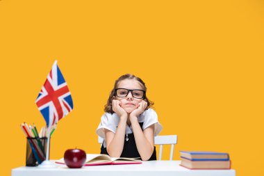 Evde ders çalışan üzgün, gözlüklü, sıkıcı, beyaz bir kız öğrenci. İngilizce dersi. Büyük Britanya bayrağı