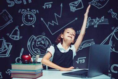 Beyaz duygusal liseli kız elini kaldırdı ve online ders sırasında dizüstü bilgisayarın başına oturdu. Uzak Öğrenme.