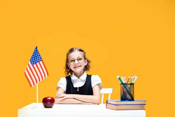 Usmívající se šťastná běloška sedící za stolem během lekce angličtiny. vlajka USA — Stock fotografie