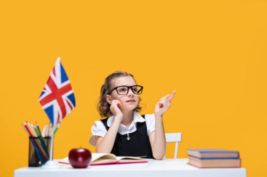 Masada kitaplarla oturan düşünceli beyaz kız öğrenci. İngilizce dersi Büyük Britanya bayrağı