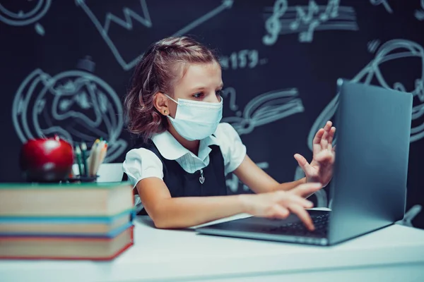 Junior student bär medicinsk mask på nätet virtuell inlärning språk klass på bärbar dator. — Stockfoto