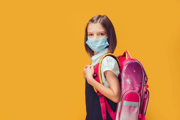 Kaukasiska skolflicka i medicinsk mask förbereder sig för att gå i skolan. Skydd av barn mot virus — Stockfoto