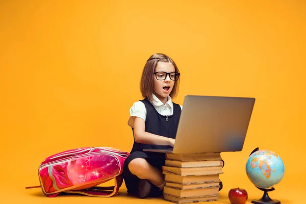 In voller Länge überrascht Schulmädchen, die hinter einem Stapel Bücher sitzt und am Laptop arbeitet. Bildung für Kinder — Stockfoto