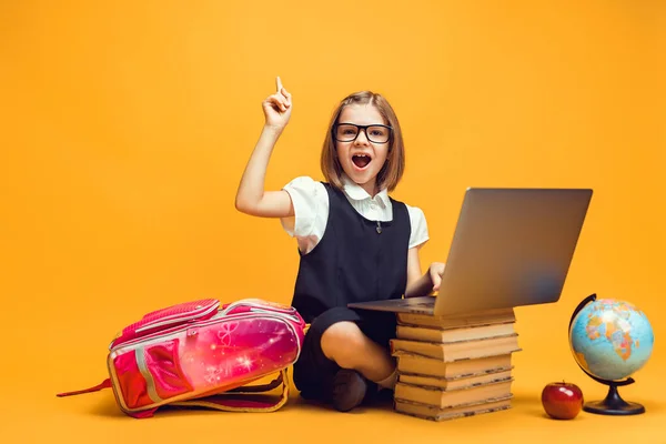 Aluno emocional senta-se atrás da pilha de livros com laptop levanta a mão com o dedo indicador. Educação infantil — Fotografia de Stock