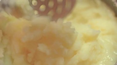 Krema veya sütle paslanmaz çelik patates ezicisi kullanarak püre yapma işlemi, yakın çekim. Lezzetli sebze ya da vejetaryen yemekleri pişirmek için adım adım tarif