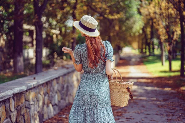 Estate indiana. Indietro di rossa donna passeggiate nel parco indossa in abito svolazzante guarda lateralmente — Foto Stock