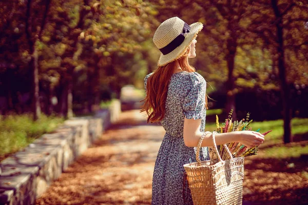 Verão indiano. Costas da menina ruiva caminha no parque olha para a estrada usa em vestido fluttering — Fotografia de Stock