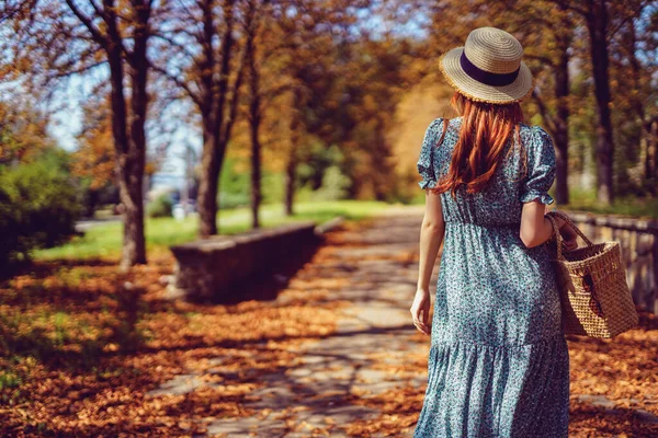 Verano indio. Espalda de mujer pelirroja camina en el parque busca la carretera lleva en vestido revoloteando — Foto de Stock