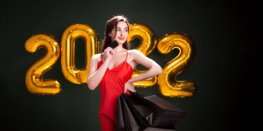 Yeni yıl alışverişi. Kara Cuma. 2022 hava altın balonu. Kredi kartı ve alışverişi olan bir kadın. satış