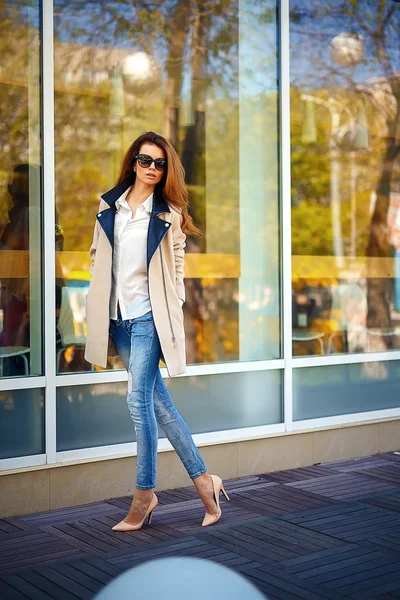 Chica en un abrigo beige y vaqueros azules — Foto de Stock