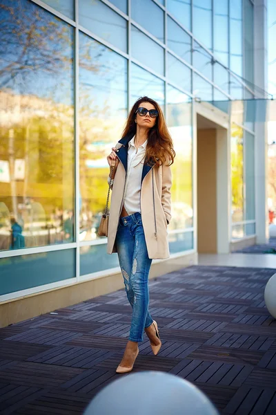 Девушка в бежевом пальто и синих джинсах — стоковое фото
