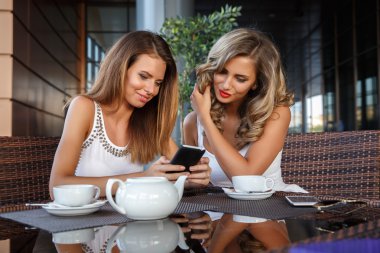 İki kız arkadaş konuşurken, kafede oturan kavramı phote, kullanarak tablet