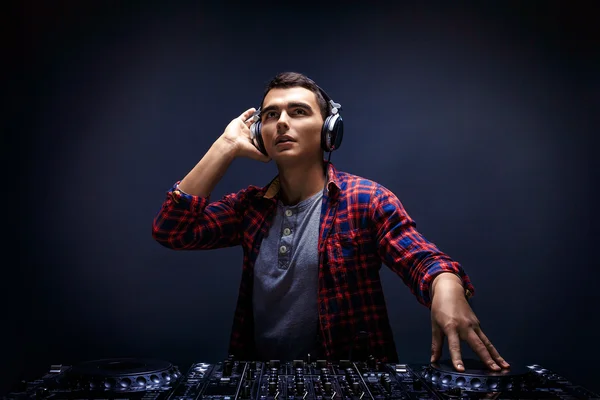 Junger Mann spielt Musik auf einem DJ-Mischpult im Studio — Stockfoto