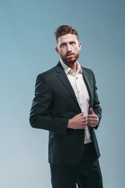 Studio shot of a stylish bearded man in elegant suit, colored tiffany background, isolate