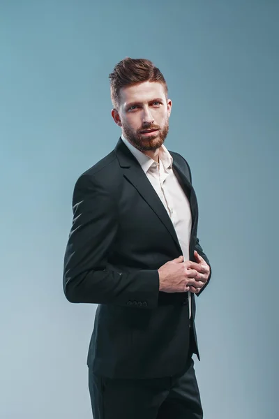 Estúdio tiro de um homem barbudo elegante em terno elegante, fundo Tiffany colorido, isolar — Fotografia de Stock