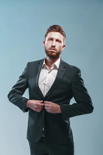 Studio shot of a stylish bearded man in elegant suit, colored tiffany background, isolate