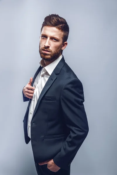 Estúdio tiro de um homem elegante em terno elegante, fundo cinza, isolar — Fotografia de Stock