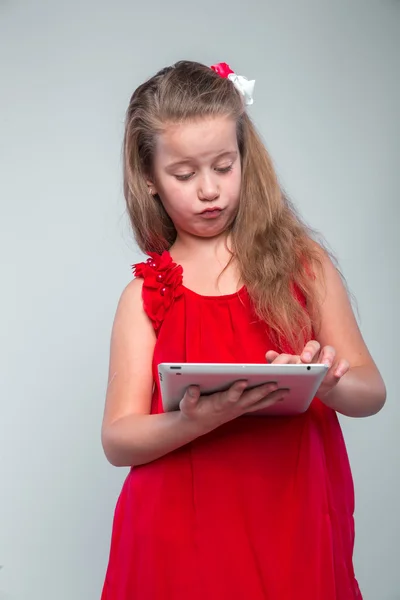 デジタル タブレットを保持している赤いドレスの女の子. — ストック写真