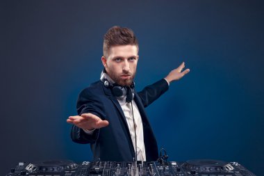 Şık saç stili ve kulaklık karıştırıcı duran koyu renkli mavi, camgöbeği arka plan üzerinde izole müzik karıştırma boyun ile kendine güvenen Dj closeup portresi