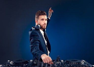 Şık saç stili ve kulaklık karıştırıcı duran koyu renkli mavi, camgöbeği arka plan üzerinde izole müzik karıştırma boyun ile kendine güvenen Dj closeup portresi