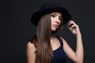 Şapkalı güzel bir kadın. Koyu arka plan.
