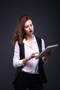 Koyu arka plan üzerinde beyaz tablet ile güzel bir kadın portresi. Stüdyo vurdu.