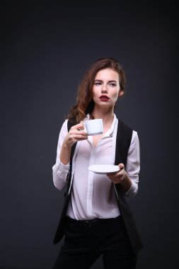 Beautiful business lady holding white cup of coffee  on a dark background. Studio shot
