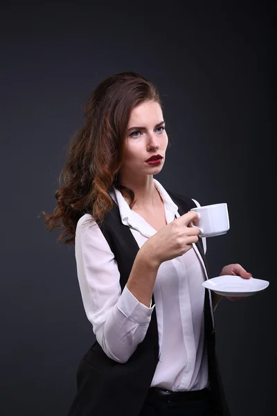 Linda senhora de negócios segurando xícara branca de café em um fundo escuro. Estúdio — Fotografia de Stock