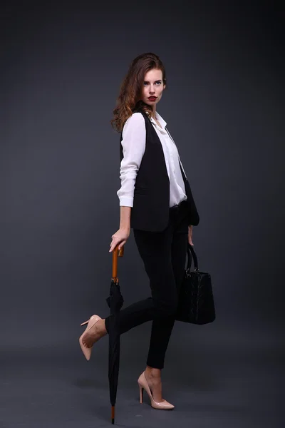 Mulher de negócios bonita com uma camisa branca de casaco preto, guarda-chuva, bolsa em um fundo escuro. Estúdio . — Fotografia de Stock