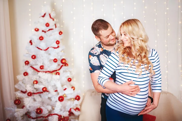 Famiglia felice nel soggiorno, dietro l'albero di Natale decorato, la luce dà un'atmosfera accogliente. Tema di Capodanno e Natale — Foto Stock